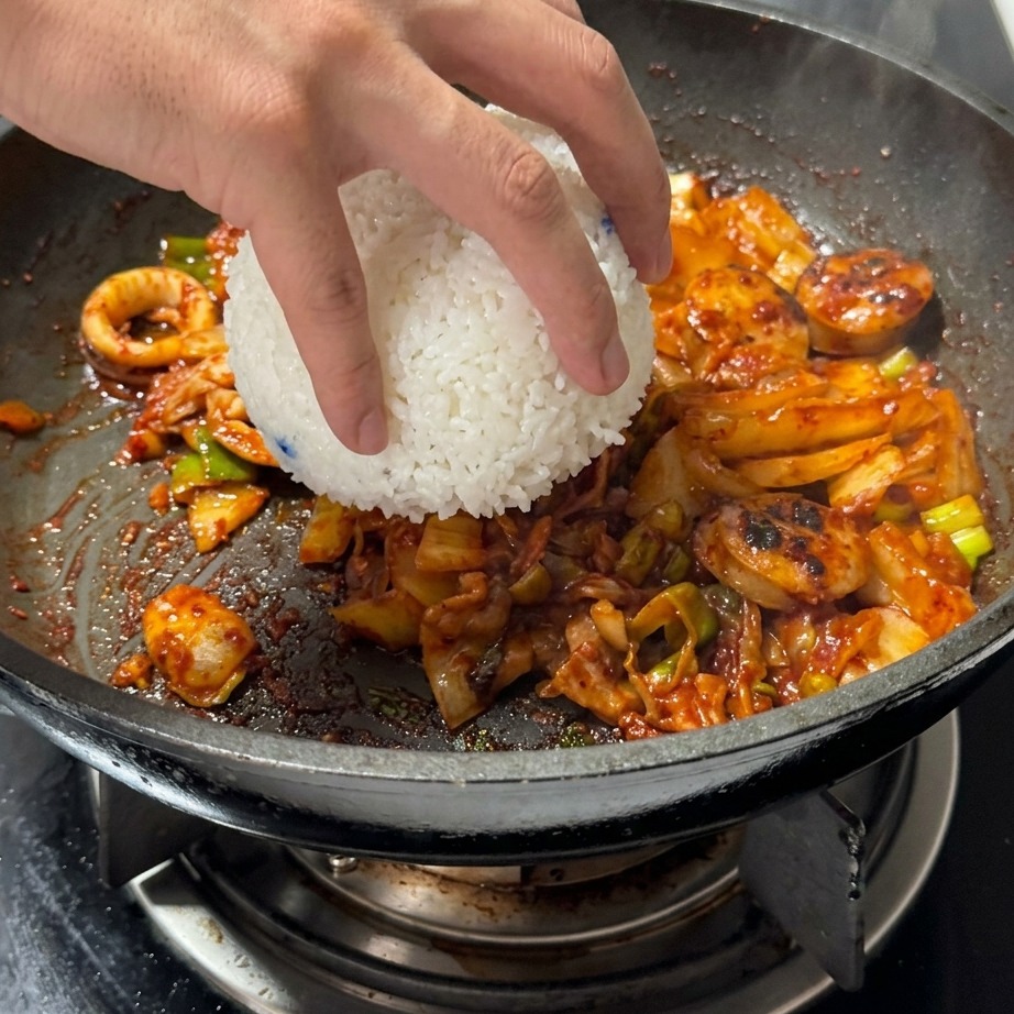Un bol de riz blanc ajouté directement dans la poêle contenant le kimchi et la viande.
