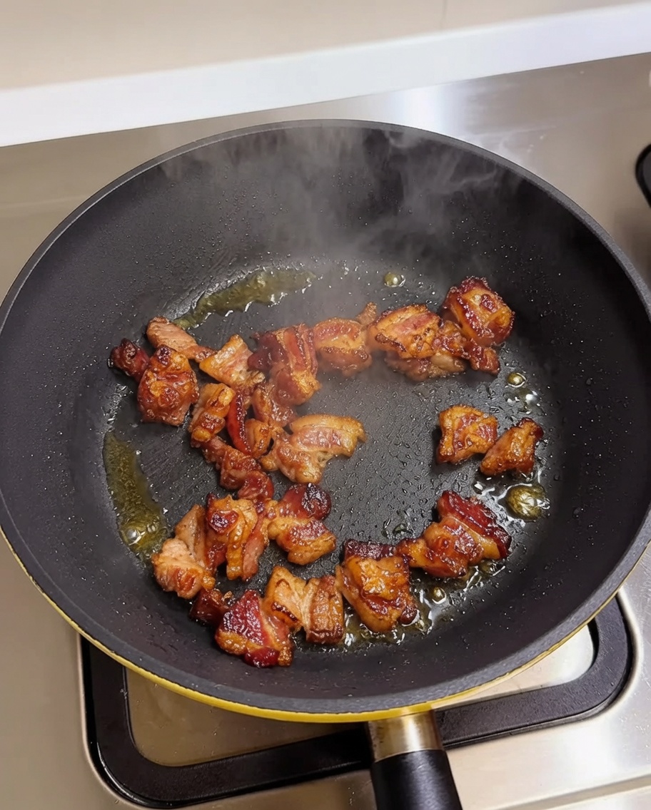 Morceaux de poitrine de porc qui dorent dans une poêle chaude.