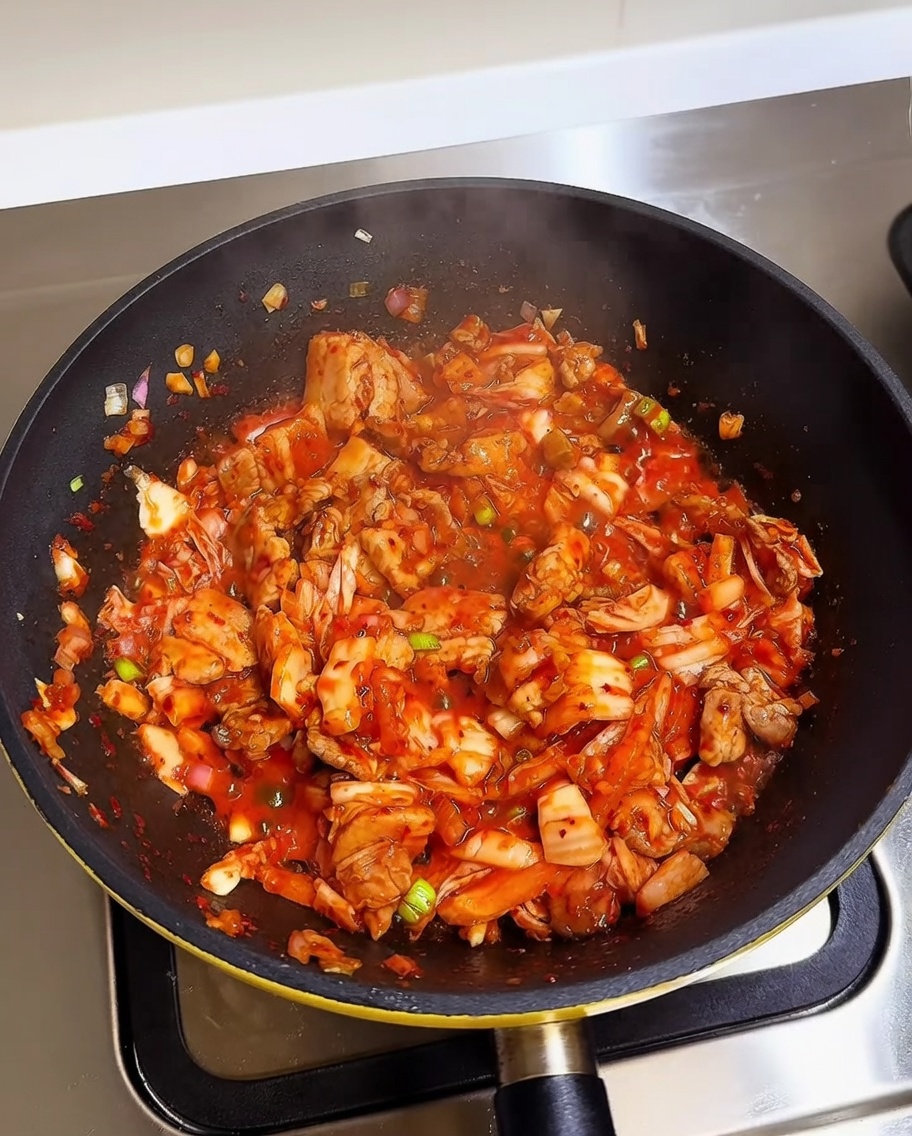 Riz blanc cuit ajouté dans une poêle contenant le mélange kimchi et porc.