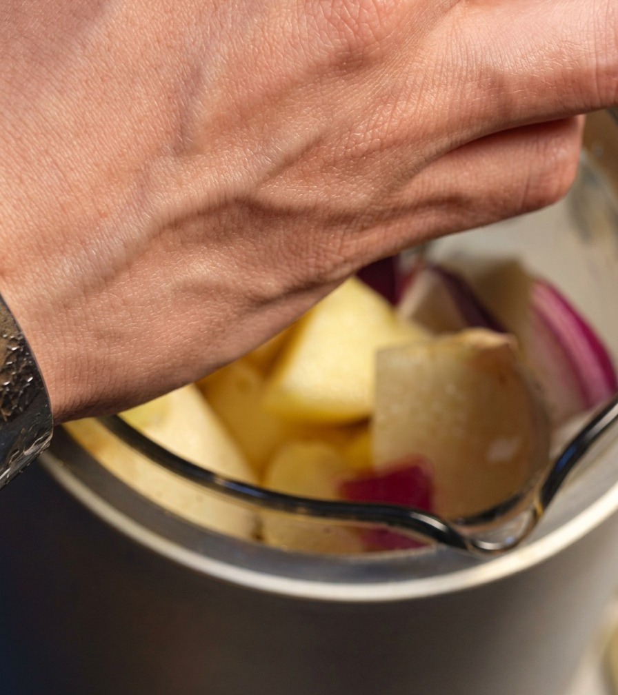 Morceaux doignon rouge, de pomme, de poire et dail ajoutés dans un mixeur.