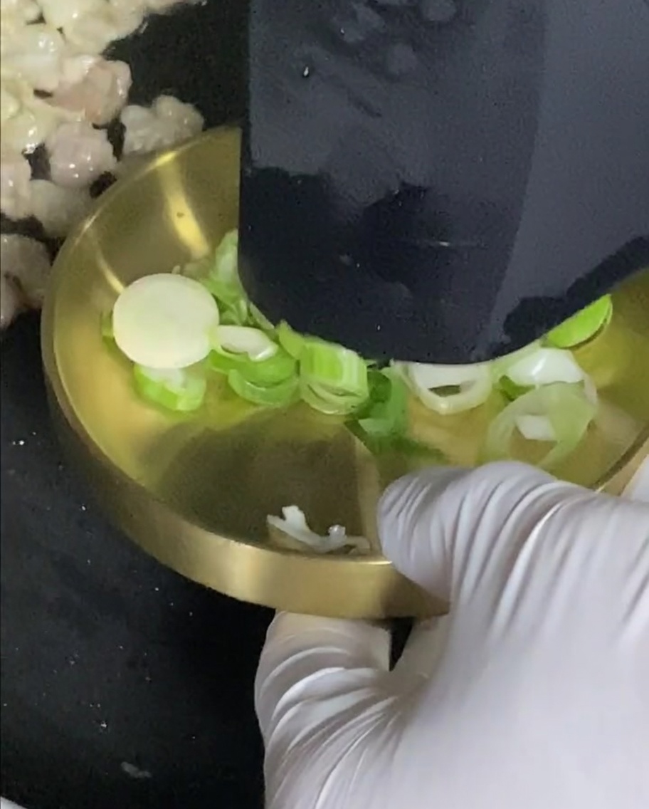 Oignons verts cuisant dans la poêle avec la poitrine de porc.