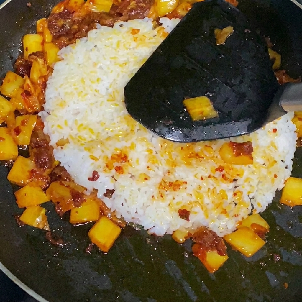 Riz sauté au kimchi en train dêtre mélangé dans la poêle.