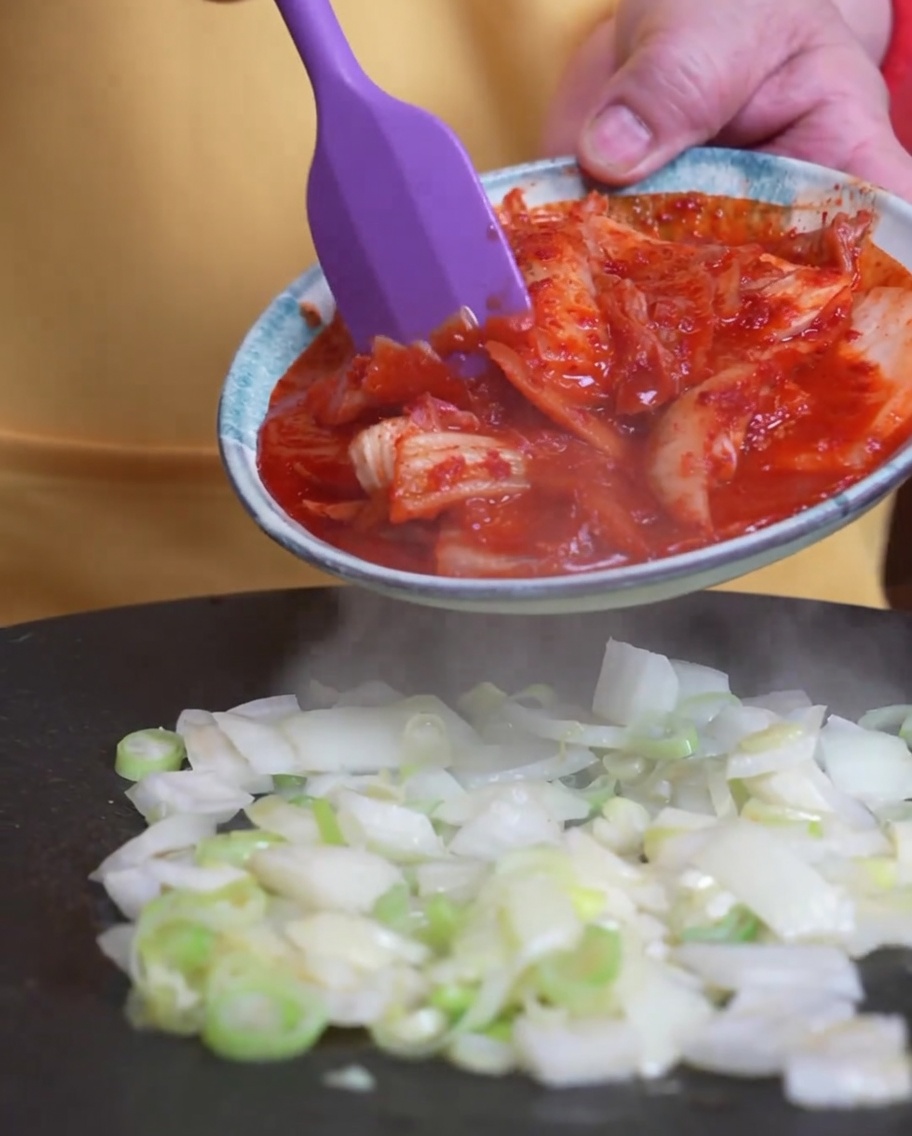 Kimchi ajouté dans la poêle où les oignons verts cuisent déjà.