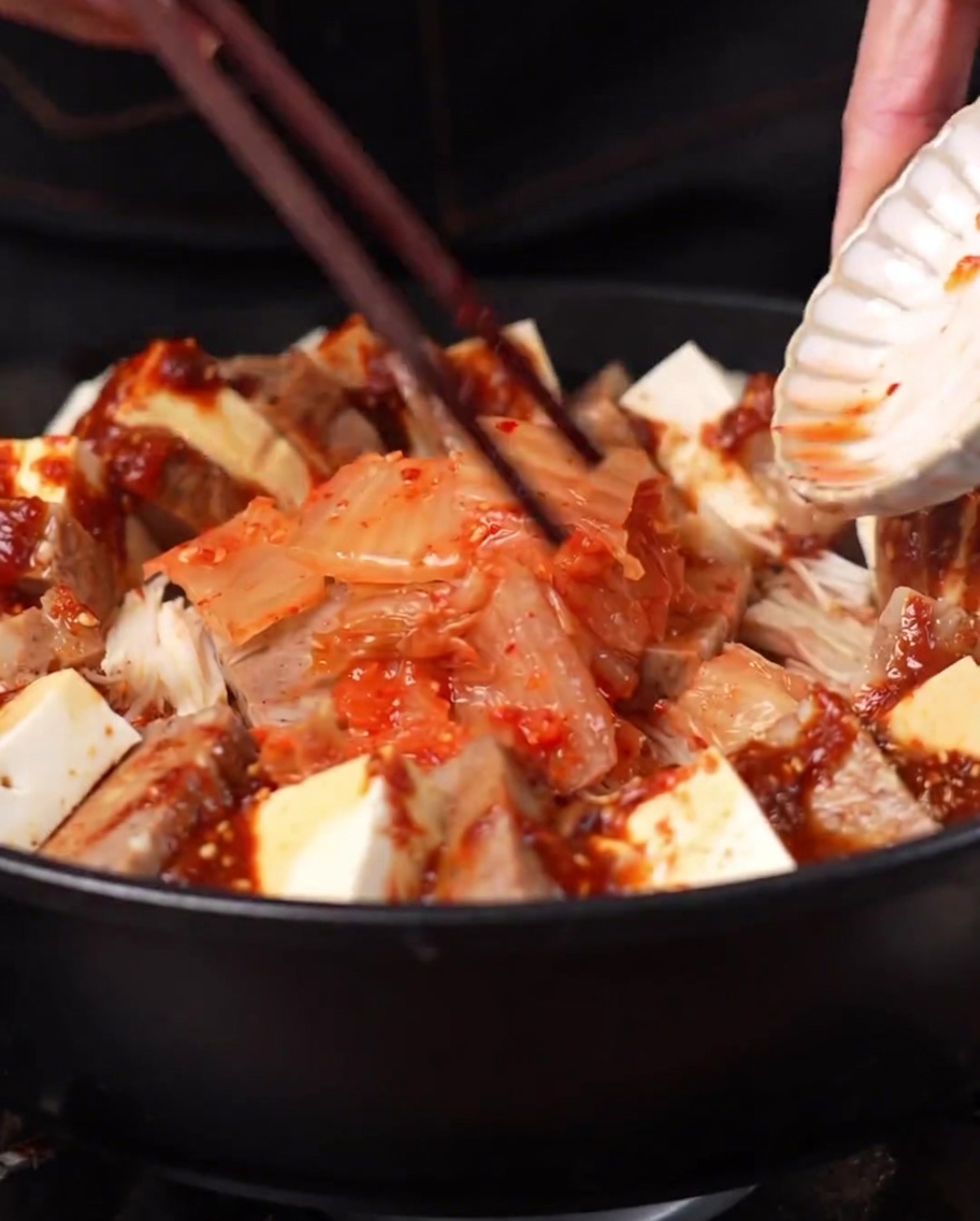 Un tas de kimchi ajouté au centre de la marmite entouré par les autres ingrédients.