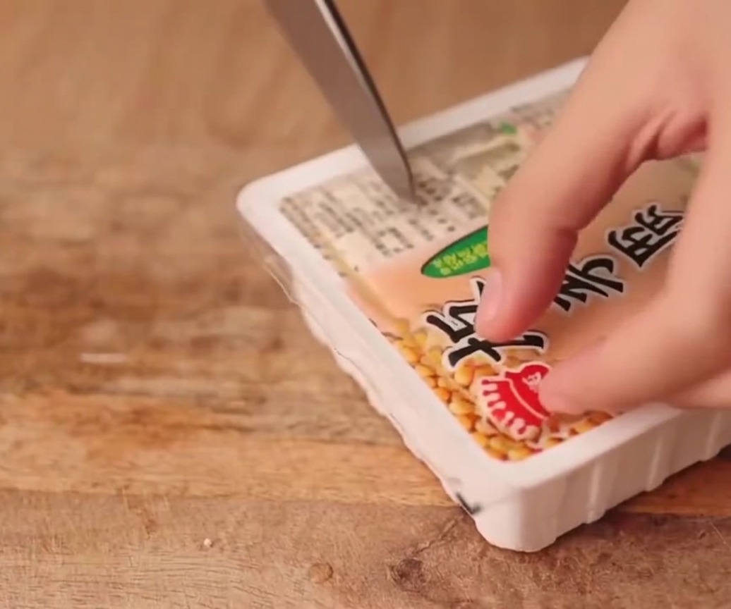 Un bloc de tofu ferme coupé en tranches nettes et uniformes sur une planche.