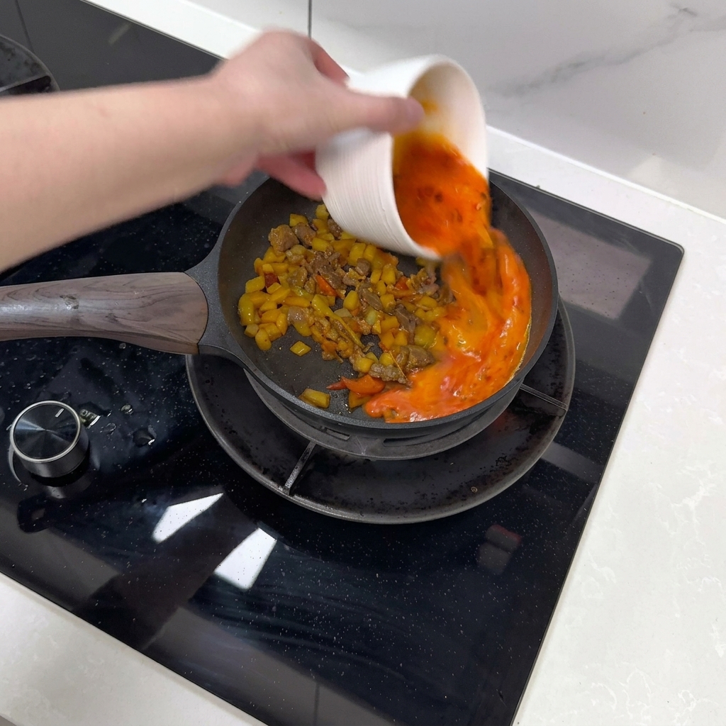 Le mélange dœufs est versé sur les ingrédients sautés.