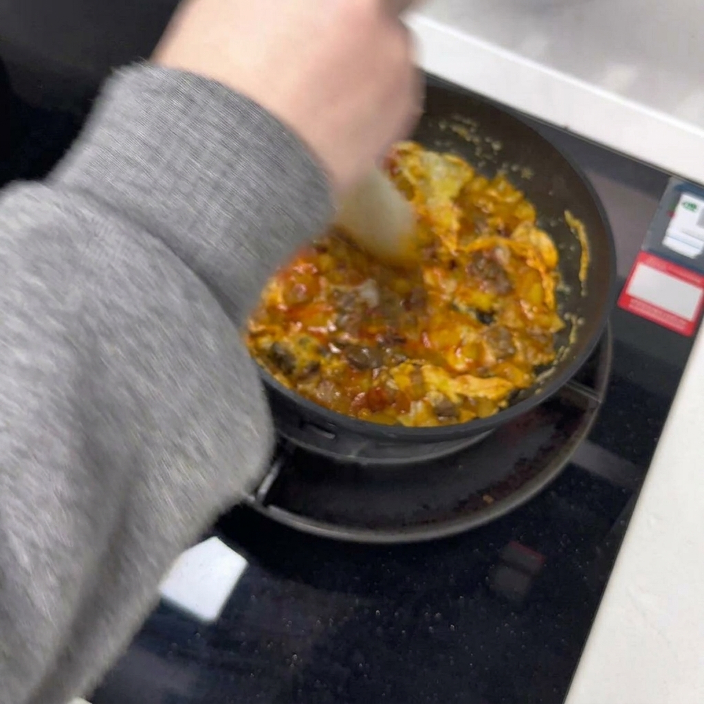 Une spatule divise lomelette en deux moitiés dans la poêle.