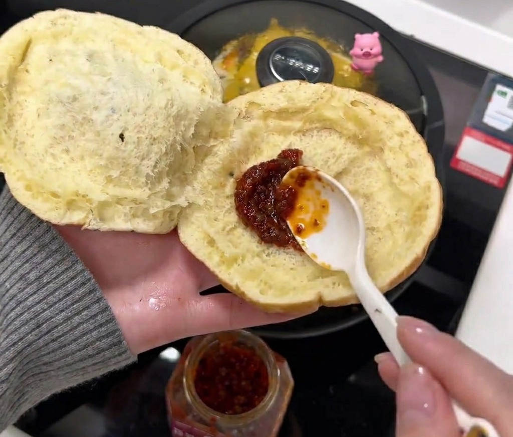 Une cuillère de sauce pimentée étalée à lintérieur dun bun ouvert.