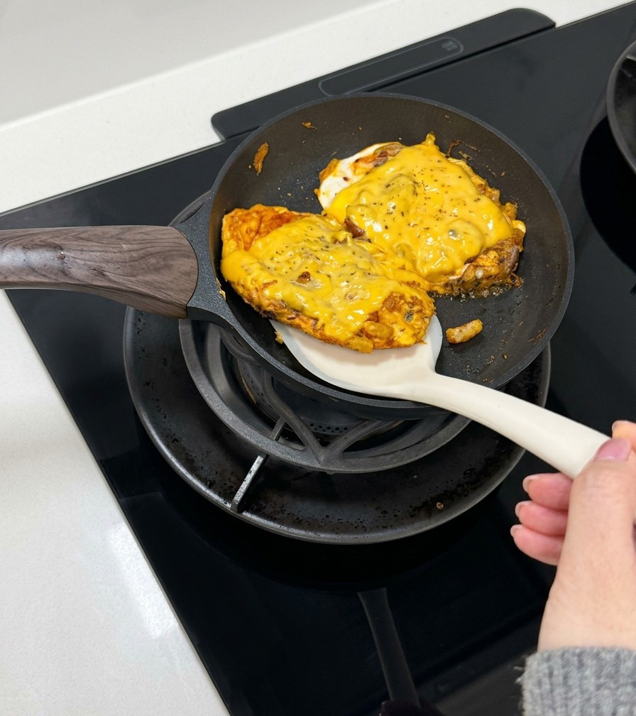 Une spatule glisse une portion domelette au bœuf et fromage dans un bun.