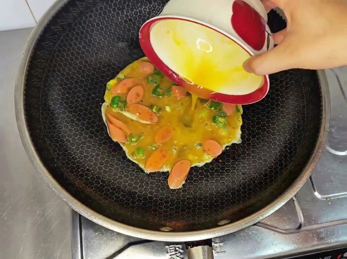 Versement du mélange dœufs dans le wok chaud.