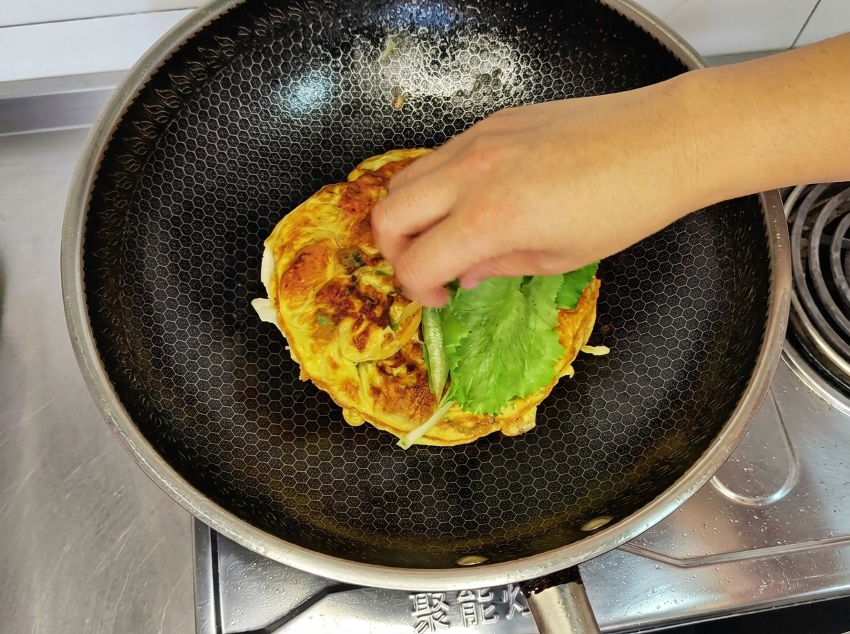 Feuille de laitue placée sur lomelette dans le wok.