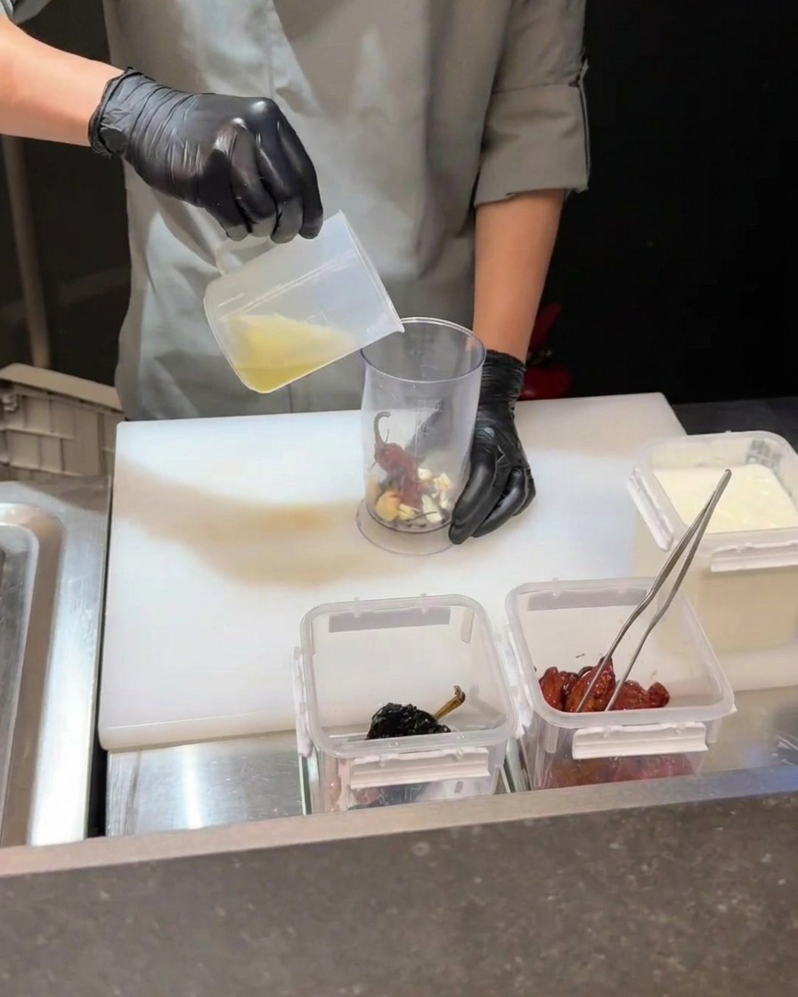 Mixeur plongeant transformant des piments, jaune dœuf et liquide en sauce.