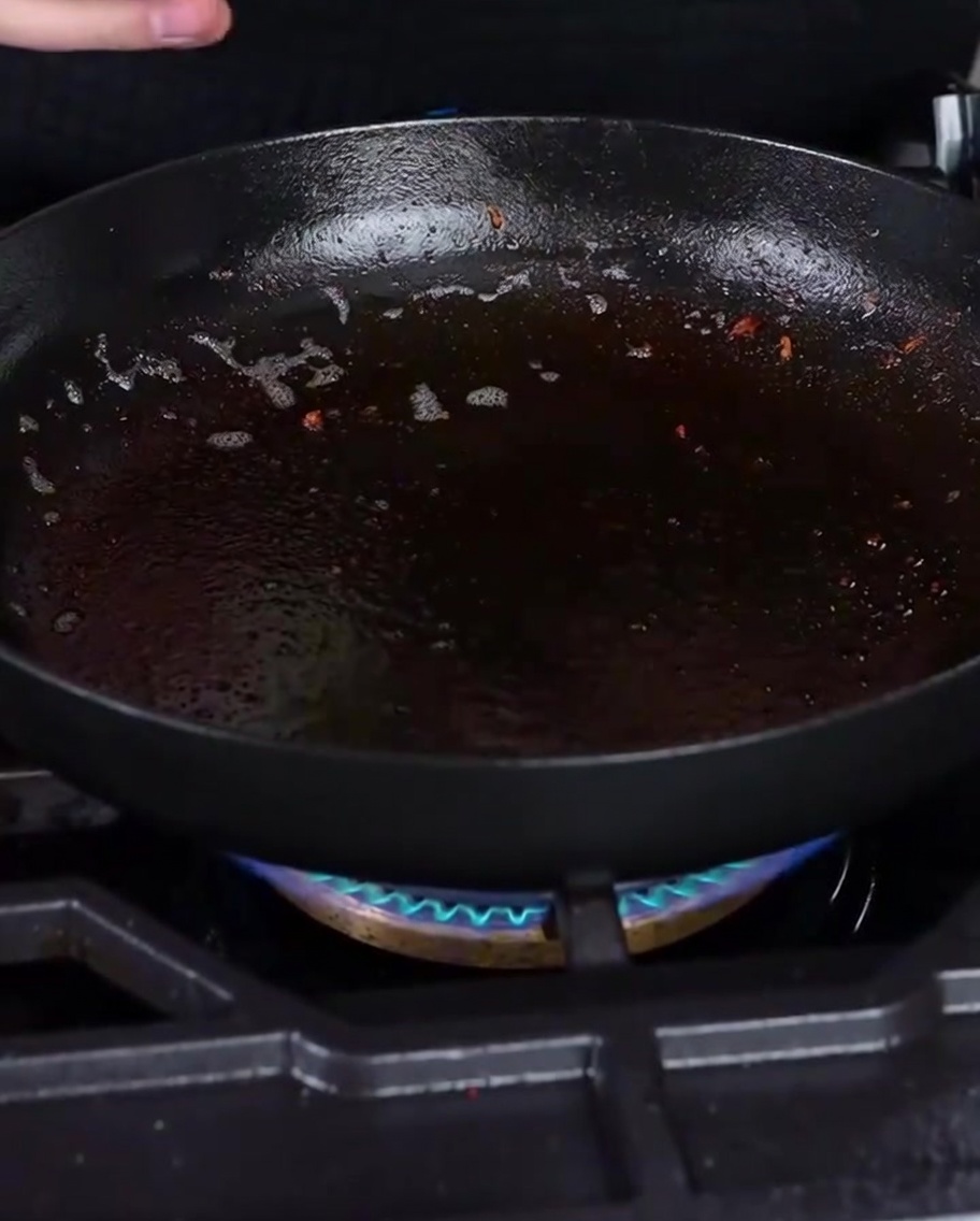 Des oignons blancs coupés en dés grésillant dans une poêle avec le reste de graisse de bacon.