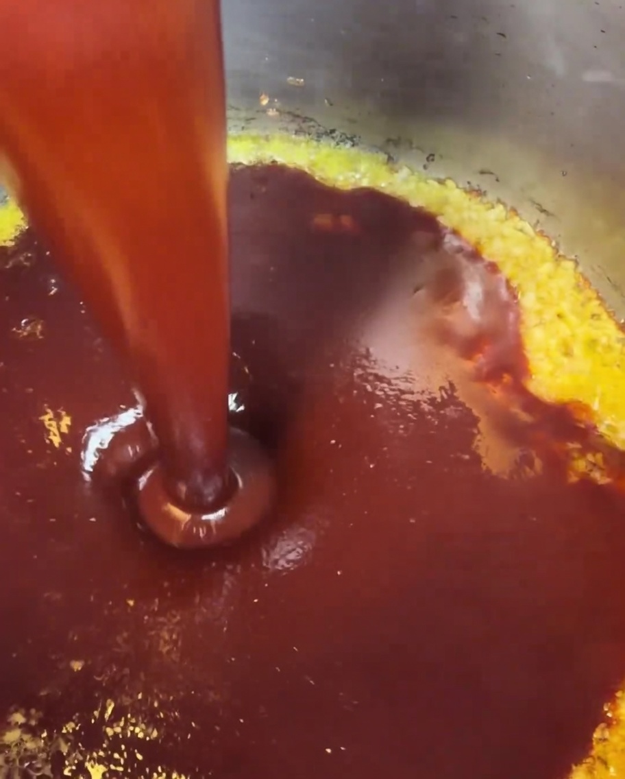 La sauce rouge mélangée versée dans une casserole où lail et le beurre mijotent déjà.