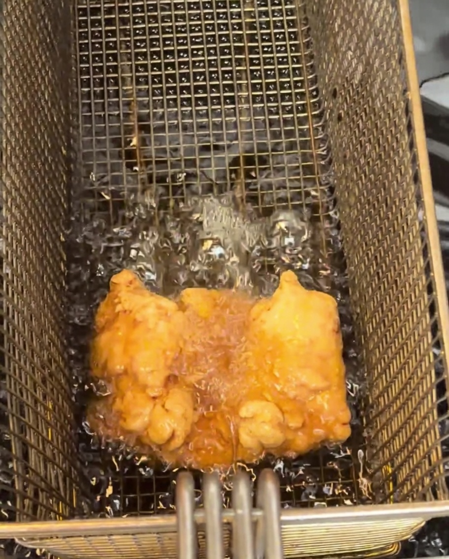 Un haut de cuisse de poulet frit doré reposant sur une grille de refroidissement.