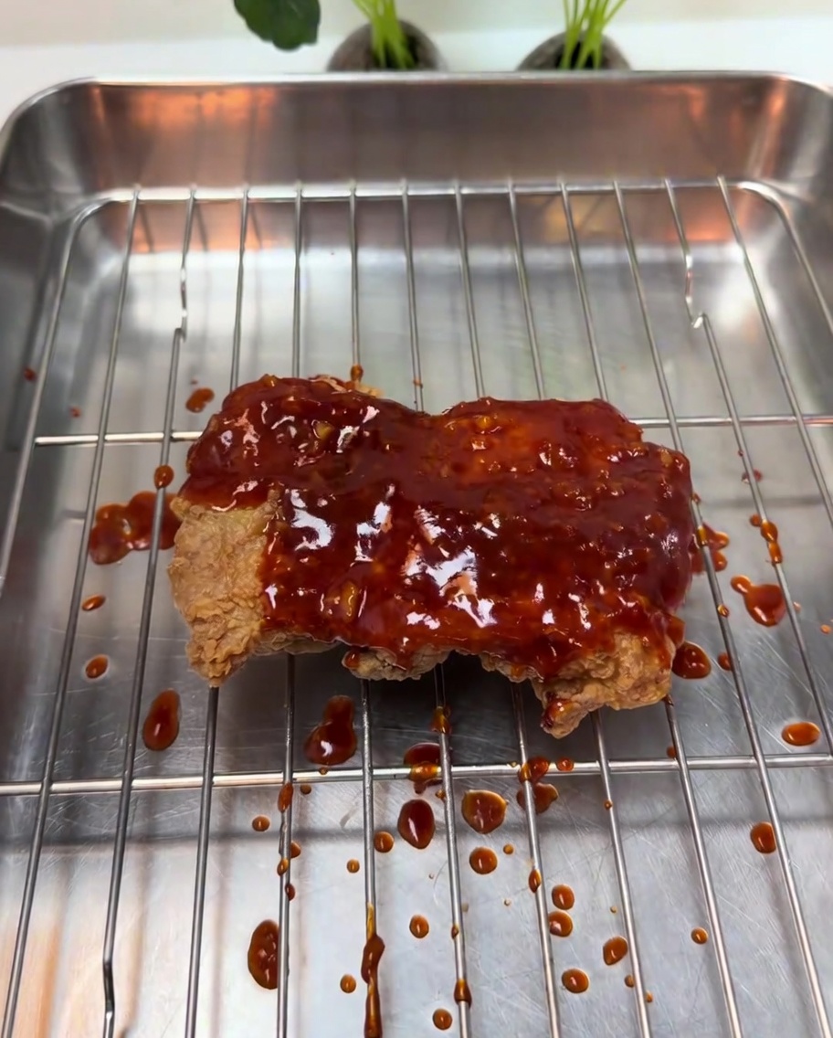 Un glaçage épais au piment rouge bouillonnant versé sur le poulet frit croustillant.