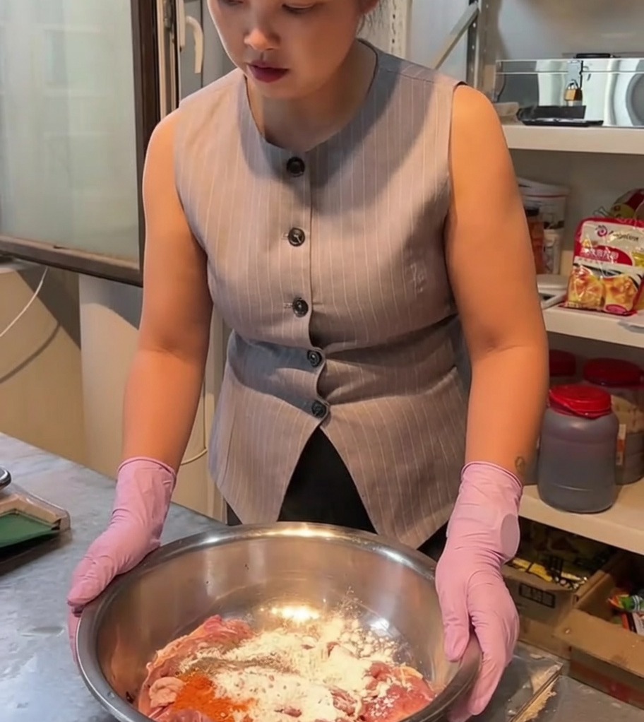 Morceaux de poulet crus mélangés avec des épices et une marinade dans un grand bol en inox.
