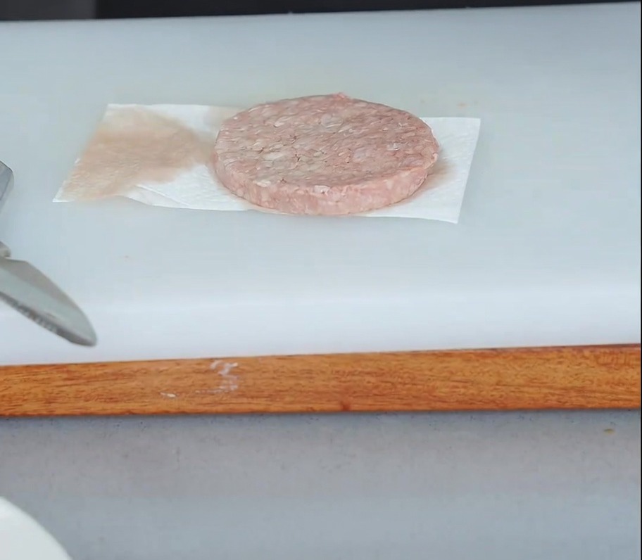 Un steak de bœuf cru posé sur du papier absorbant avec un autre papier pressé dessus pour absorber lhumidité.