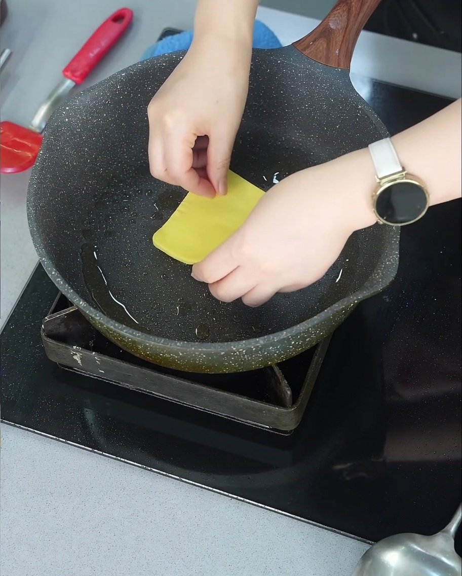Une tranche de fromage jaune commençant à fondre sur un steak de bœuf doré dans une poêle.
