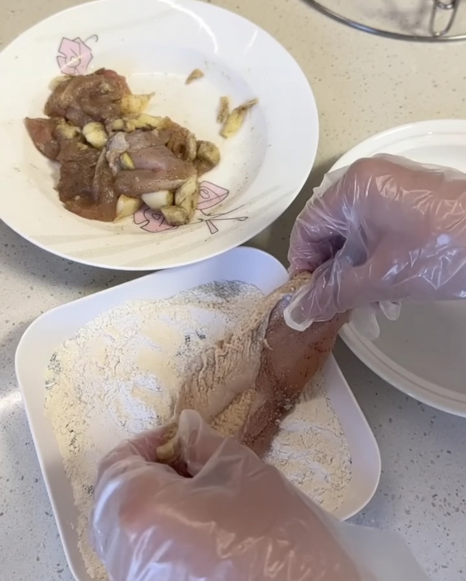 Morceaux de poulet pressés dans un mélange à panure sur une assiette blanche.