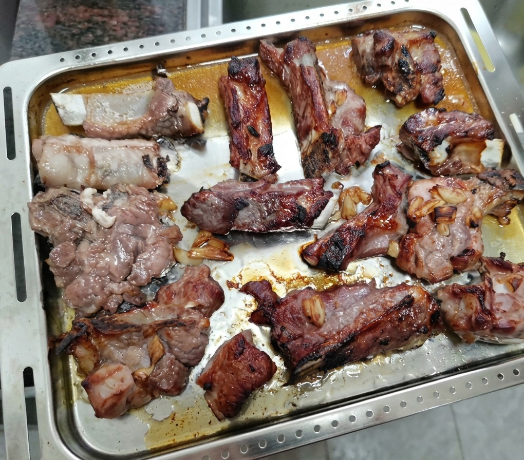 Travers de porc partiellement rôtis sur une plaque, prêts à être badigeonnés de miel.