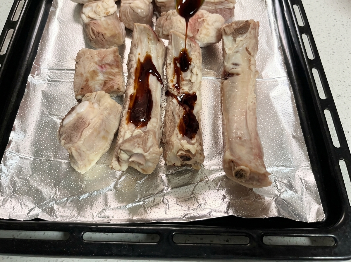 De la marinade épaisse versée à la cuillère sur les travers de porc posés sur la plaque.