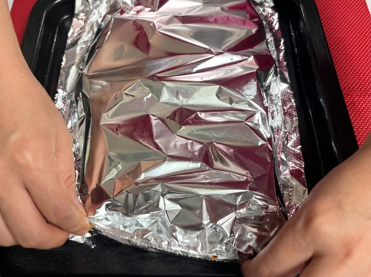 Une feuille daluminium scellée hermétiquement sur la plaque de travers de porc.