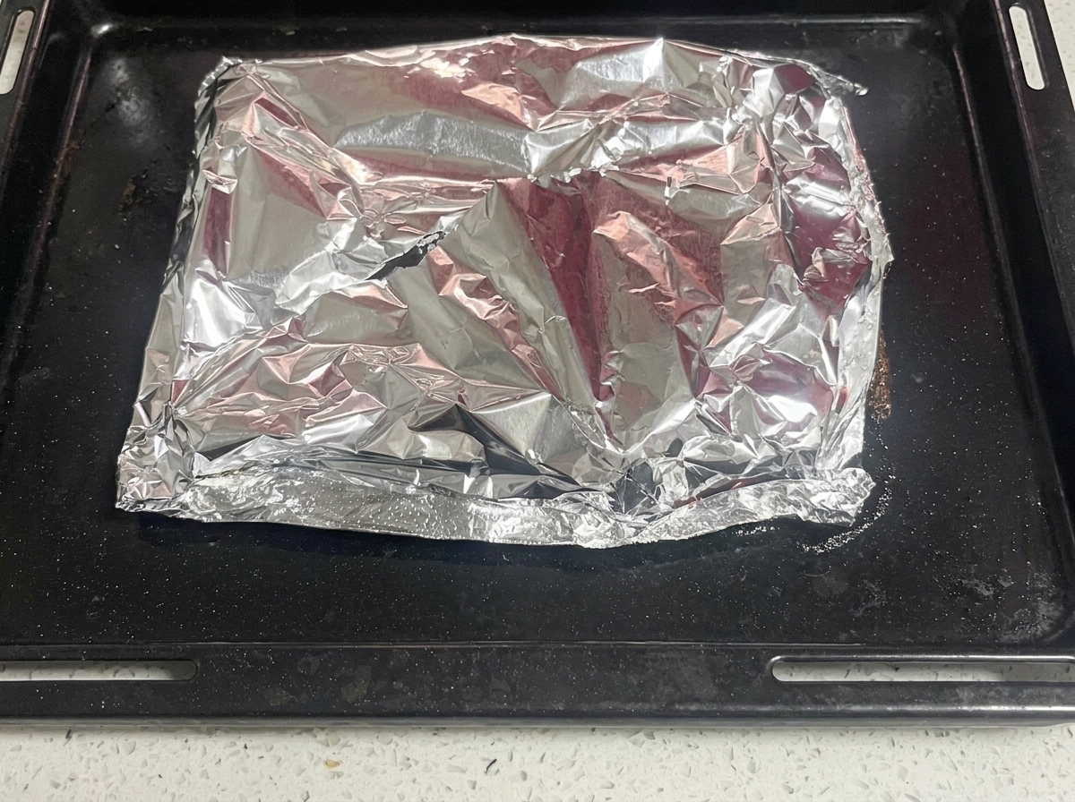 Un couteau fendant la feuille daluminium supérieure pour révéler la viande cuite et fumante.
