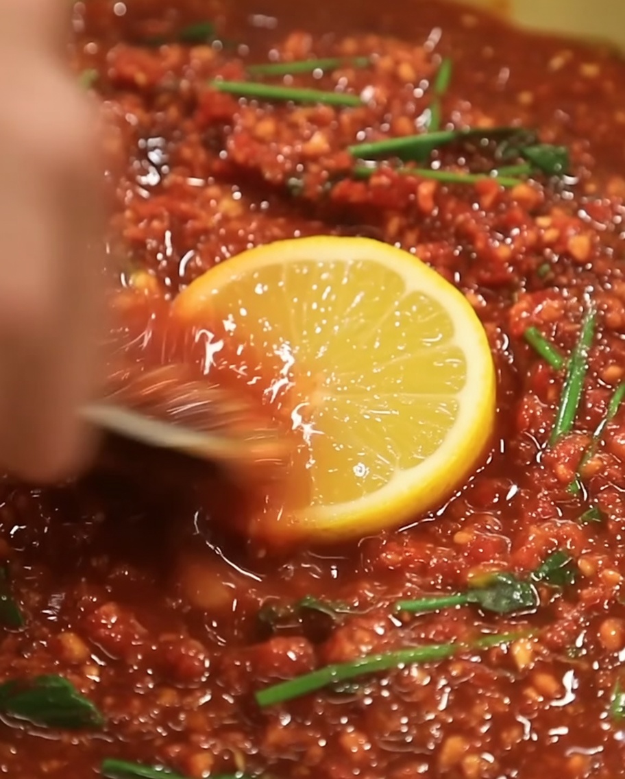 Une petite quantité dhuile de sésame dorée versée au centre de la marinade rouge foncé.