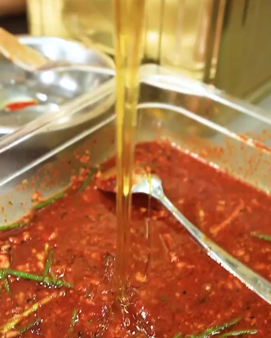 Gros plan sur le sirop de maltose versé dans la marinade rouge.
