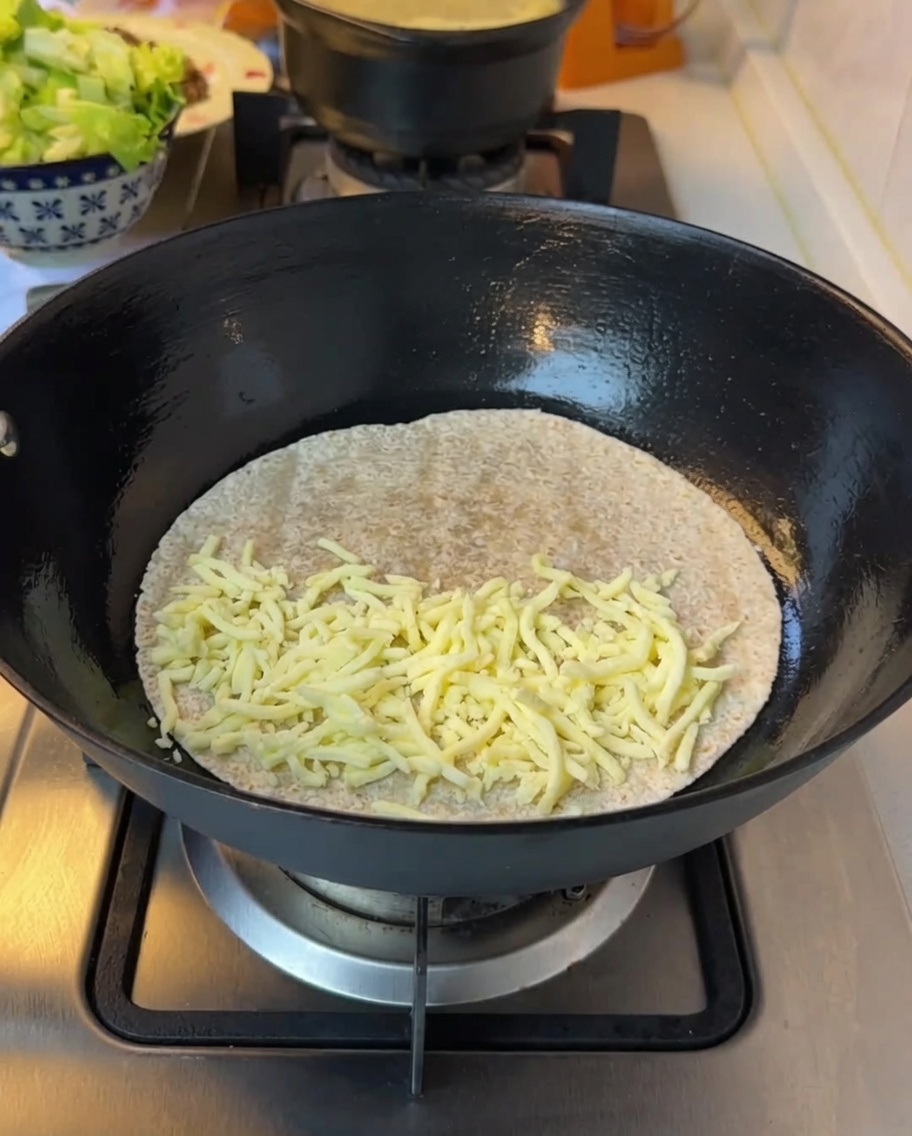 Laitue ciselée ajoutée sur le fromage fondu sur la tortilla.