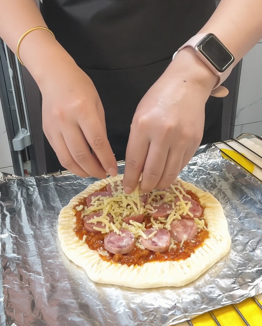 Dernière poignée de mozzarella parsemée sur la pizza, suivie dun léger saupoudrage de persil séché.