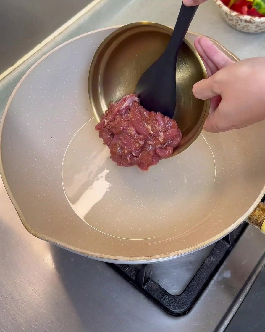 Tranches de porc marinées versées dans une poêle chaude légèrement huilée.