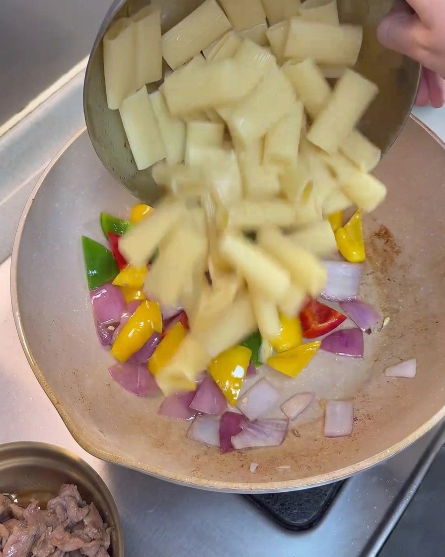 Rigatoni cuits ajoutés à la poêle contenant les poivrons et les oignons sautés.