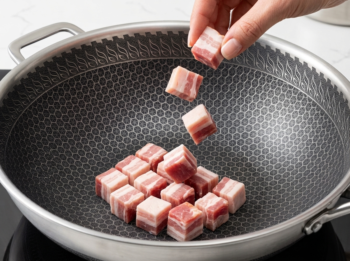 Morceaux de bacon qui dorent dans une poêle avec le gras fondu au fond.