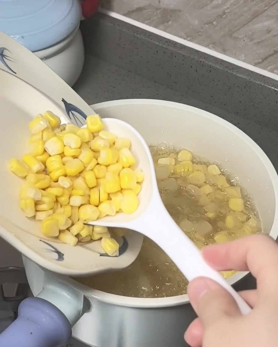 Grains de maïs et châtaignes deau écrasées ajoutés à une casserole deau sucrée bouillante.
