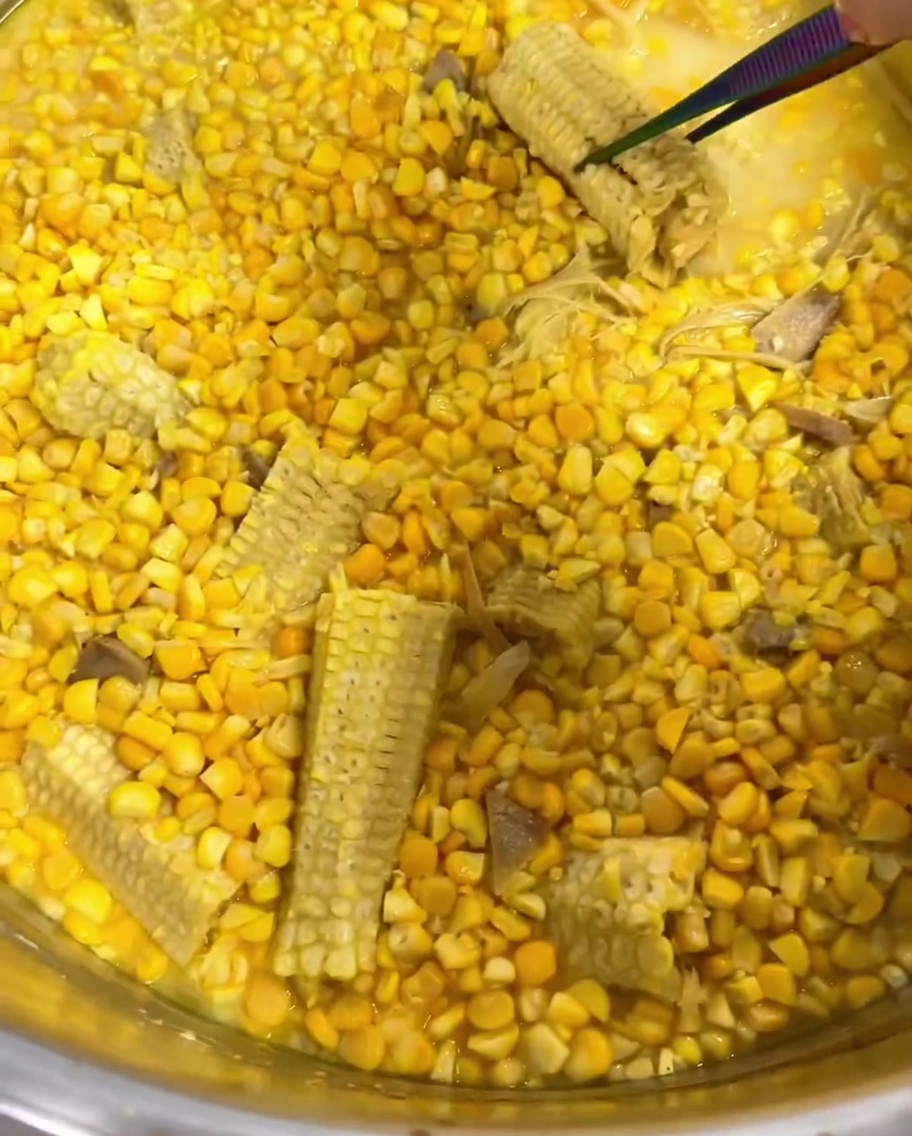 Pinces retirant la citronnelle et une rafle de maïs dune casserole de soupe mijotée.