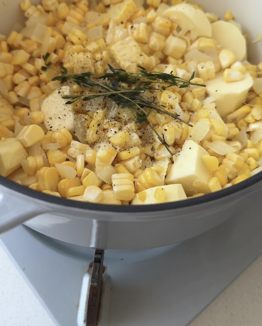 Eau claire versée dans une casserole sur les légumes et une branche de thym frais.