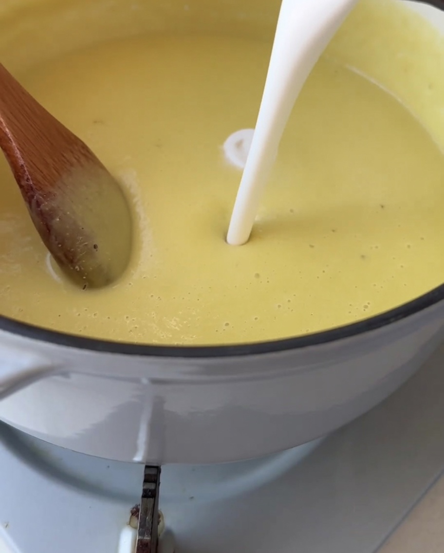 Crème versée dans une casserole contenant le velouté de maïs jaune.