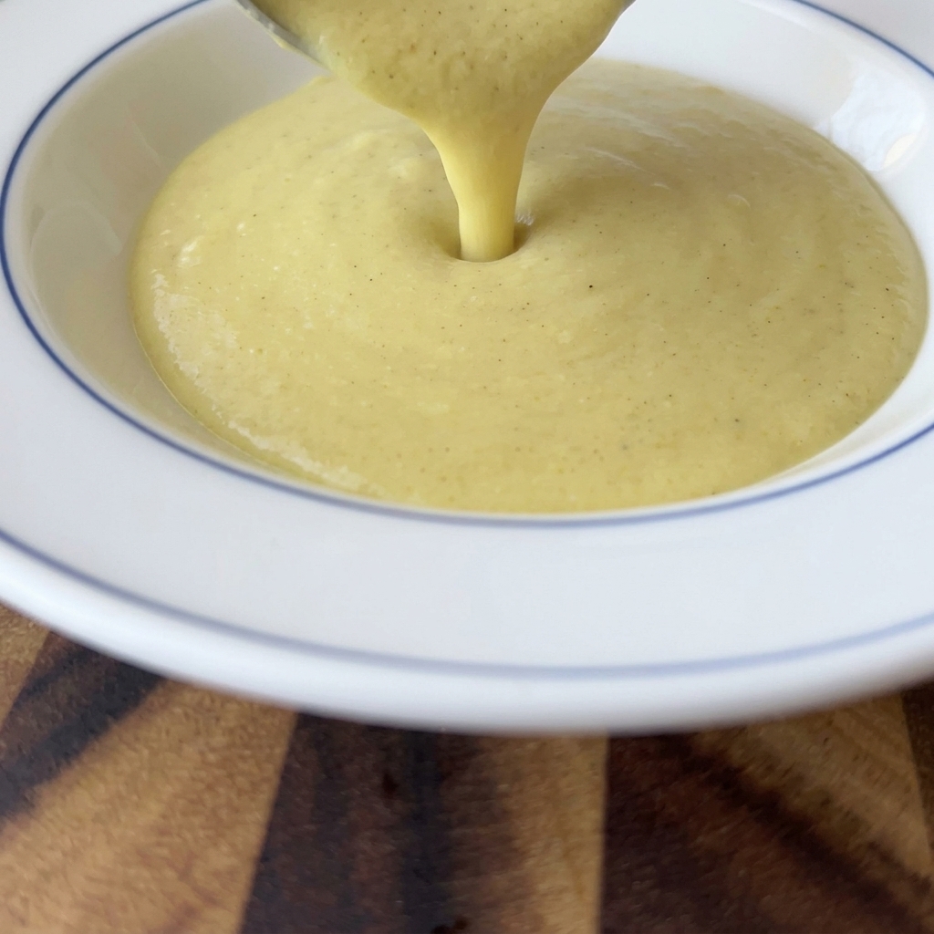 Le velouté de maïs onctueux versé à la louche dans un bol blanc.