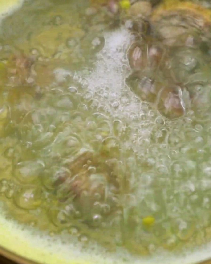 Des palourdes ajoutées dans une casserole deau de cuisson du maïs à laide dune passoire.