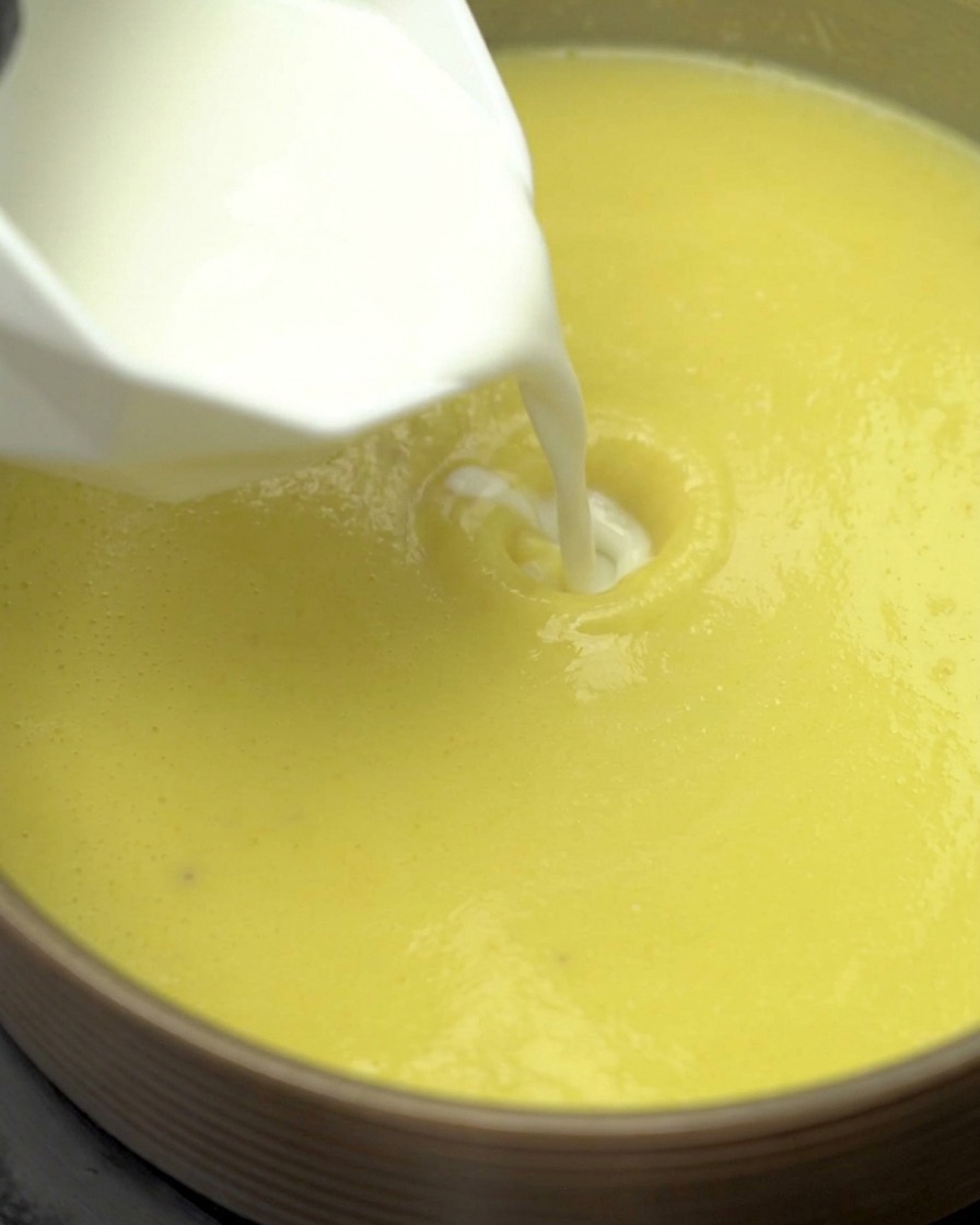 Lait et crème liquide versés dans la soupe de maïs frémissante.