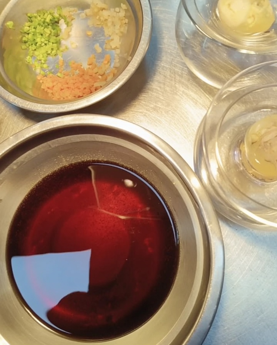 Vue rapprochée de petits contenants en métal contenant de lail haché, de la coriandre fraîche finement ciselée et des carottes en dés, préparés pour garnir la gelée.