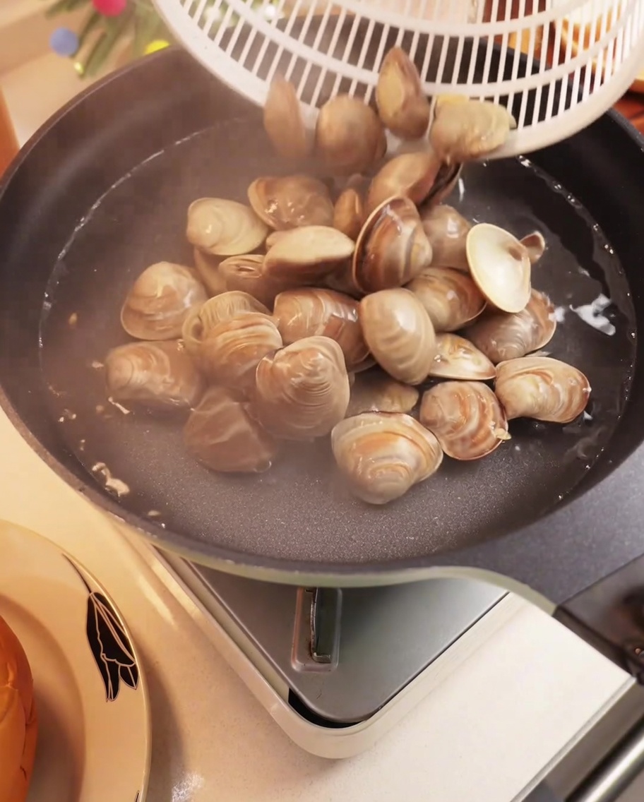 Palourdes fraîches bouillant dans une casserole deau, les coquilles commençant à souvrir.