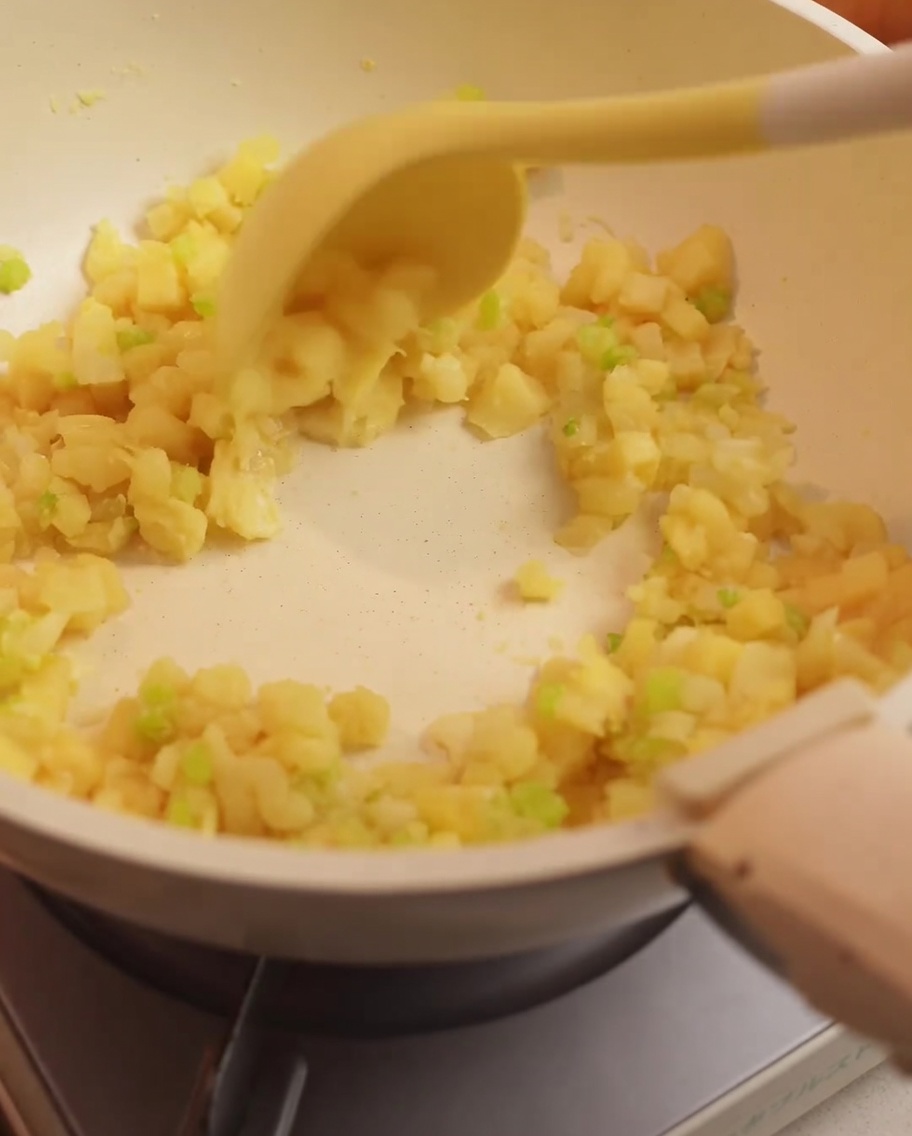 Bouillon de palourdes versé dans la poêle contenant les légumes sautés et la farine.