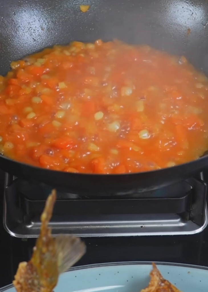 Eau bouillante versée dans un wok contenant les pommes de terre et tomates.