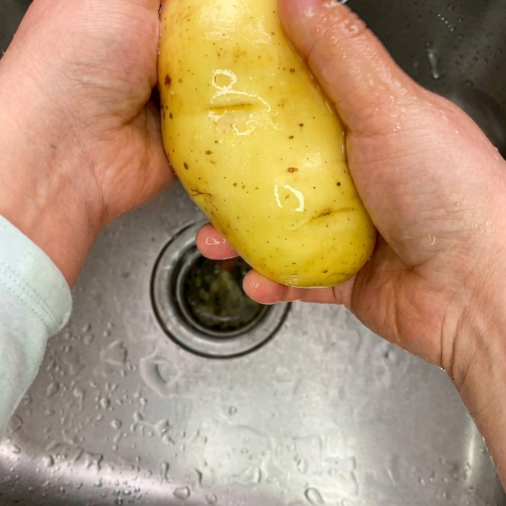 Bâtonnets de pomme de terre crue sur une planche à découper en bois propre.