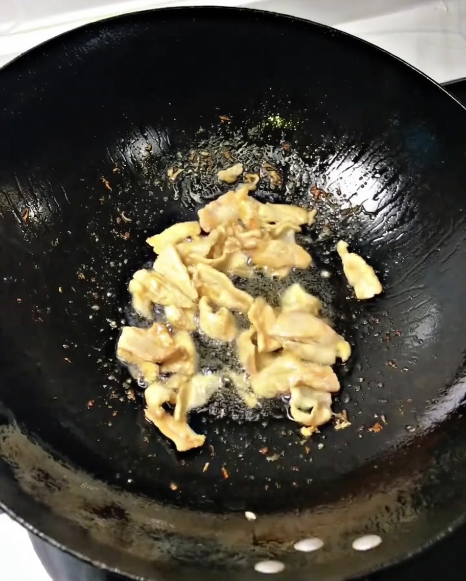 Oignon vert et gingembre ajoutés au porc dans un wok chaud.