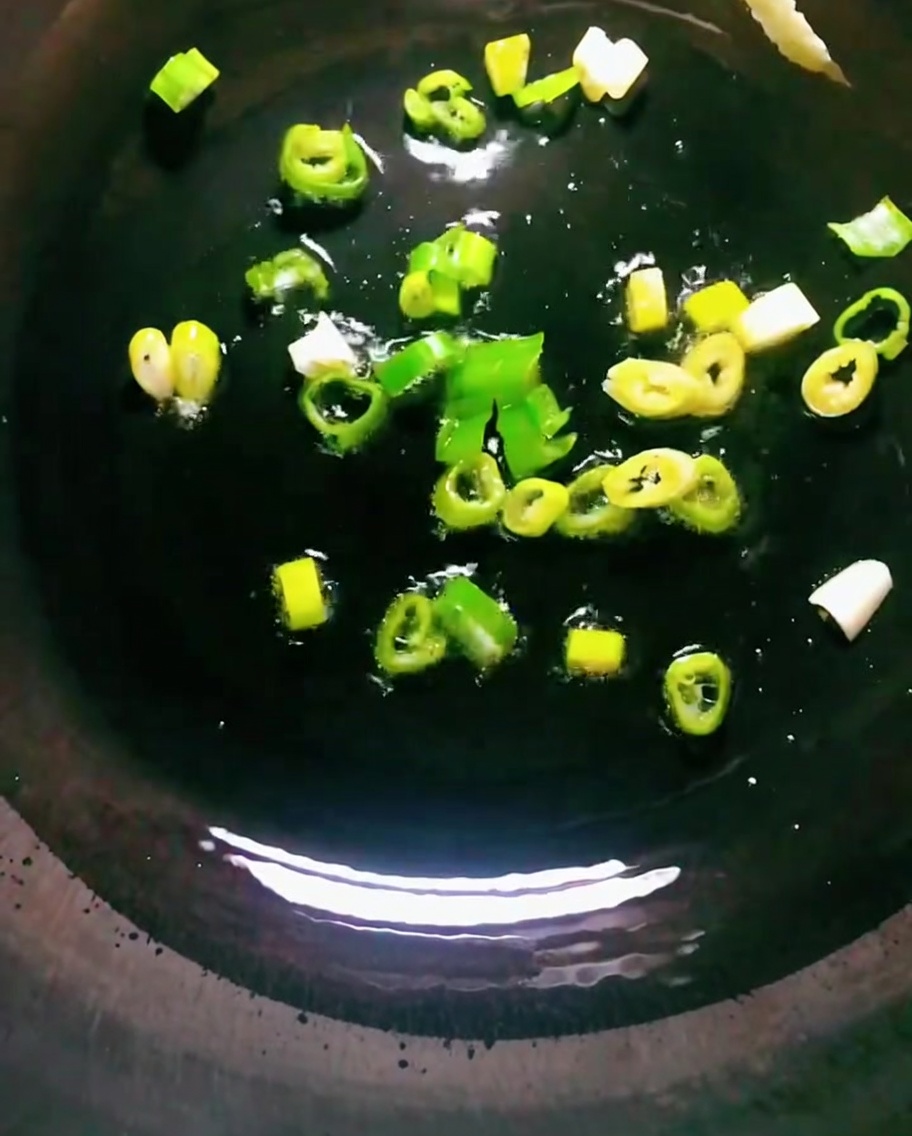 Oignons verts en train de revenir dans de lhuile chaude dans un wok.