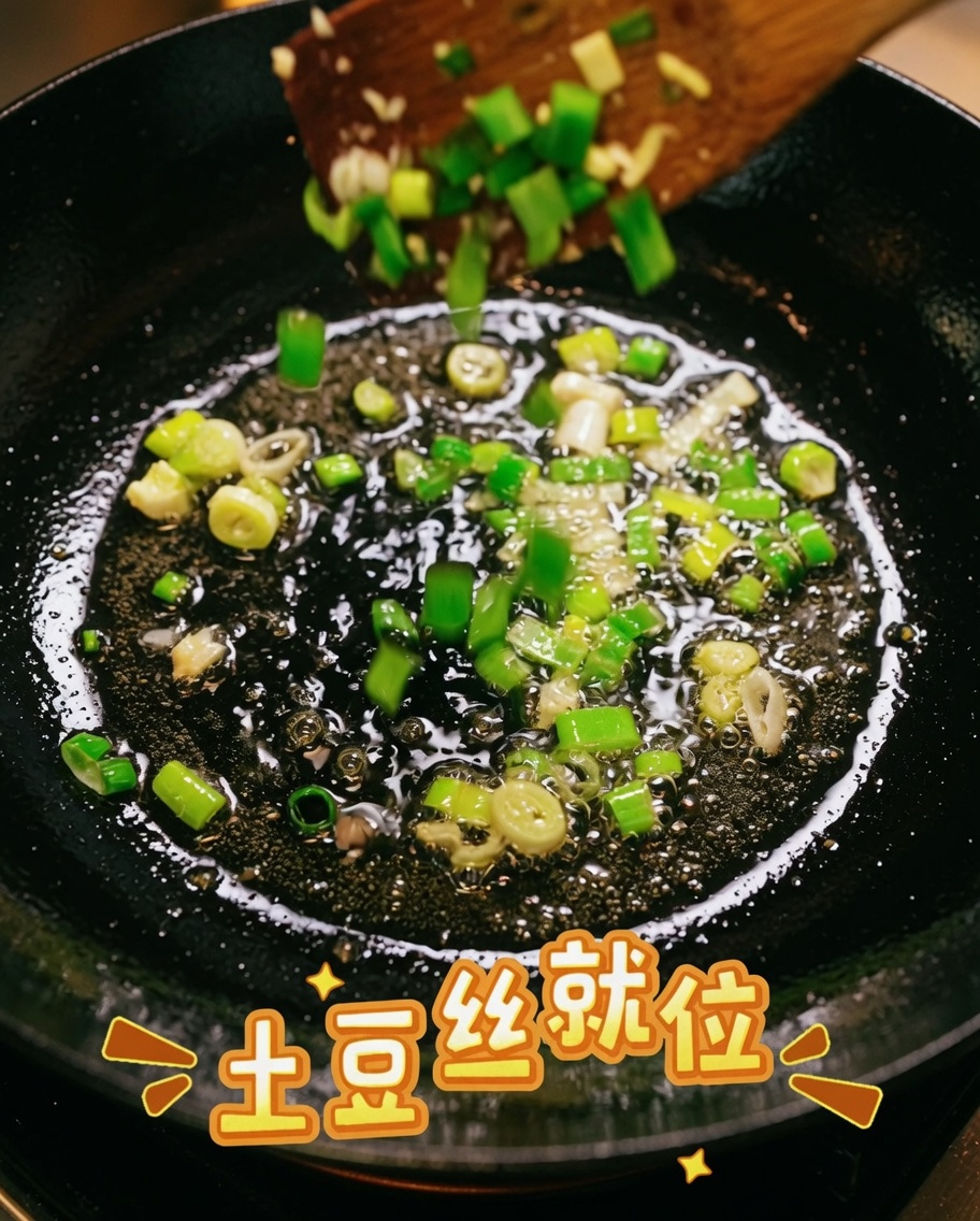 Pommes de terre râpées mélangées avec des oignons verts sautés dans une poêle.